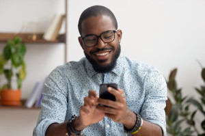 Happy african american businessman using phone mobile apps at workplace