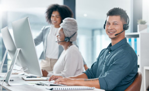 Call center, customer service and telemarketing consultant man and diversity team working in crm office. Contact us, teamwork and support male employee typing on pc and wearing headset for support