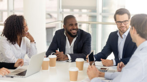Happy diverse businesspeople talk at negotiations sit at office table